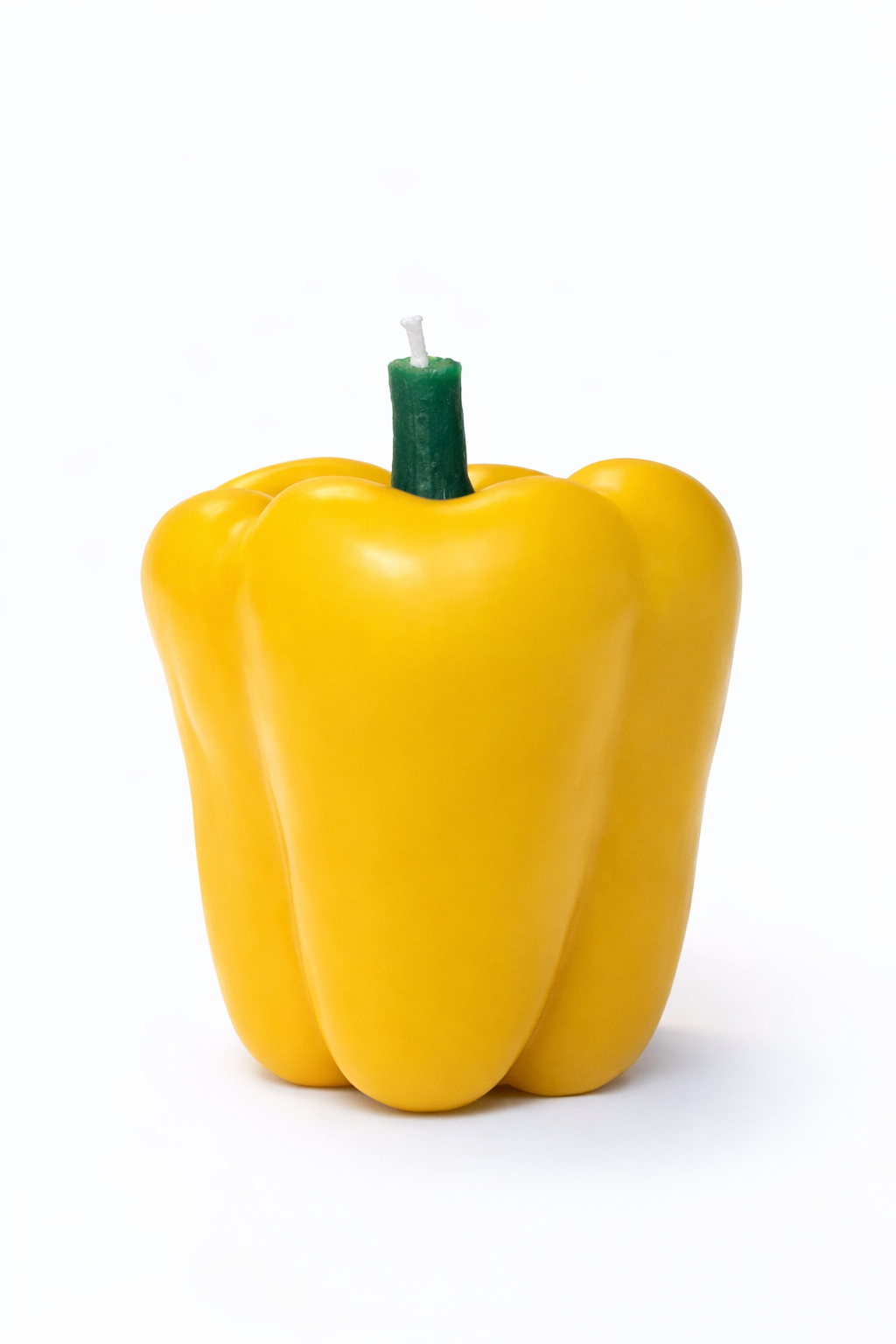 Yellow bell pepper-shaped candle on a white background